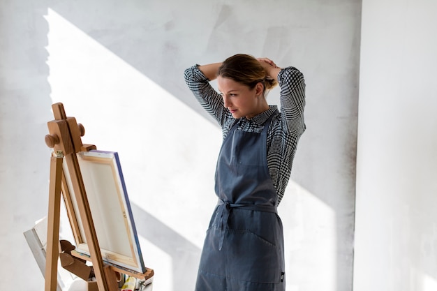 Free photo woman at studio with canvas and easel