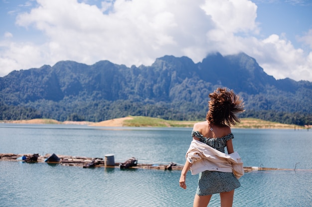 Free photo woman in summer dress and jacket tourist travel in thailand, khao sok national park, amazing view on boats and lake.