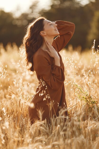 Woman in a summer field. Brunette in a brown sweater. 