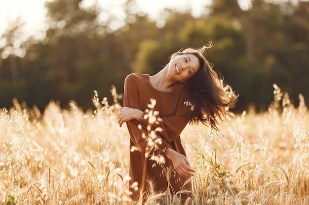 Free Photo woman in a summer field. brunette in a brown sweater. 