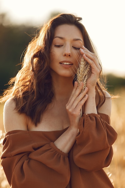 Woman in a summer field. Brunette in a brown sweater.