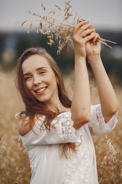 Woman in a summer field. Brunette in a white dress. 