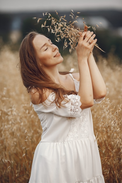 Woman in a summer field. Brunette in a white dress. 