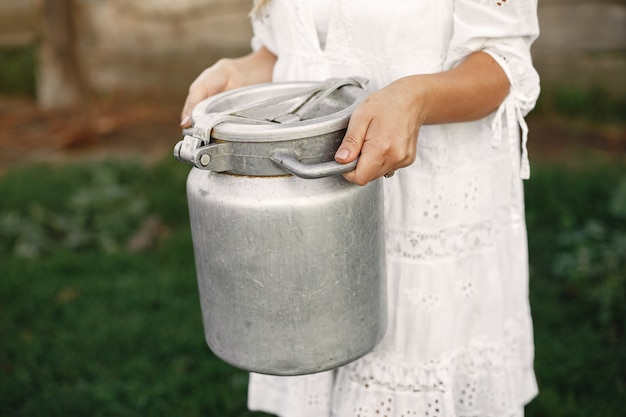 Free photo woman in a summer field. girl in a white dress. woman with barrel of milk.