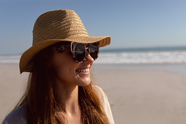 Woman in sunglasses and hat relaxing on the beach