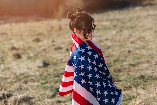 Woman in sunglasses wrapped in American flag 