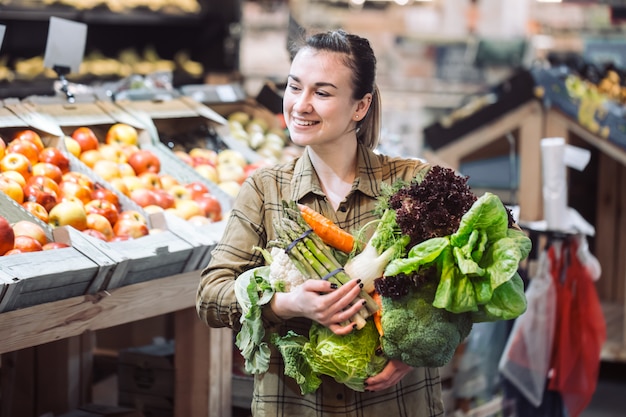 Woman in the supermarket. Beautiful young woman shopping in a supermarket and buying fresh organic vegetables