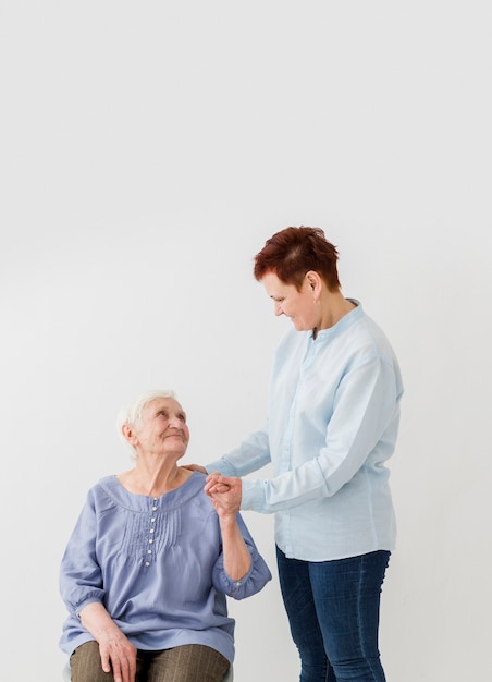 Free photo woman supporting elder woman with copy space