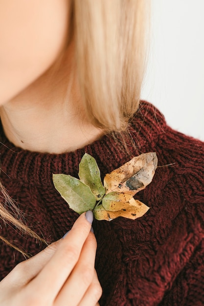 Free photo woman in a sweater holding crisp leaves during fall season