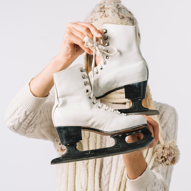 Woman in sweater holding white skates