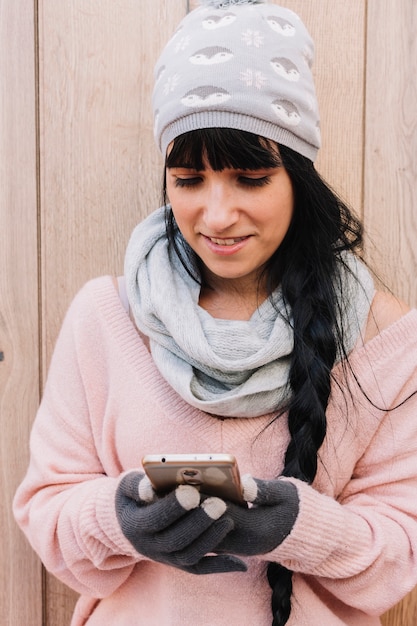 Free photo woman in sweater looking at smartphone