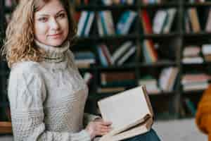 Free photo woman in sweater near blurred bookshelves