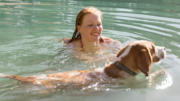 Woman swimming and playing with dog in the water