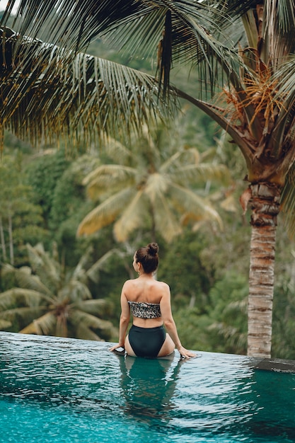 Free Photo woman in a swimming pool on a jungle view