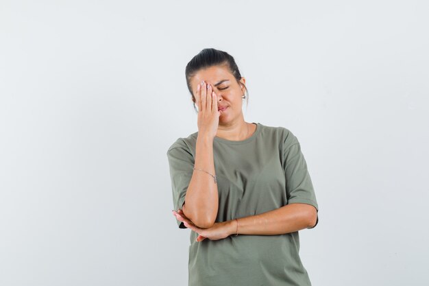 woman in t-shirt holding hand on face and looking thoughtful