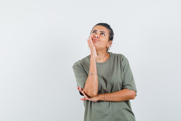 woman in t-shirt standing in thinking pose and looking indecisive