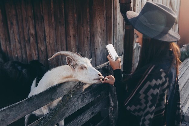 Free photo woman takes a photo of a goat on her smartphone