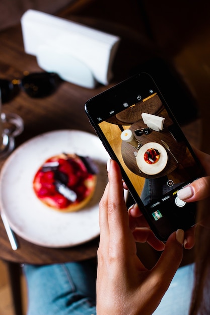 Free photo woman takes photo of her dessert with smartphone