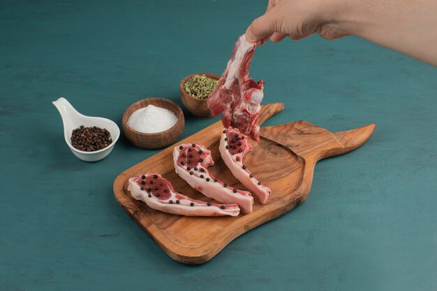 Woman takes a piece of uncooked meat from wooden board.