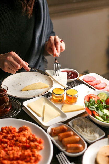 Woman takes some cheese from the plate