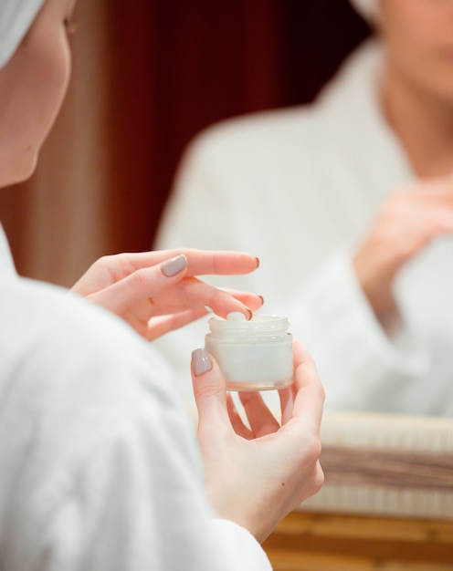 Woman taking face-cream with her finger in the bathroom