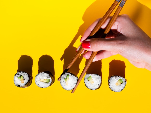 Free Photo woman taking a nigiri roll from a yellow table