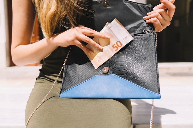 Free photo woman taking out money from her hand bag