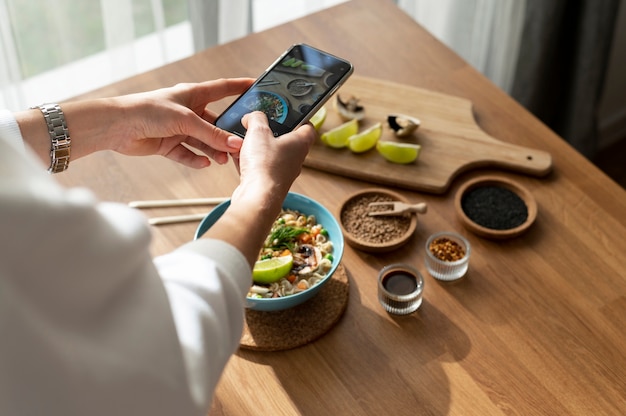 Free photo woman taking photo of bowl of ramen and sliced lemon