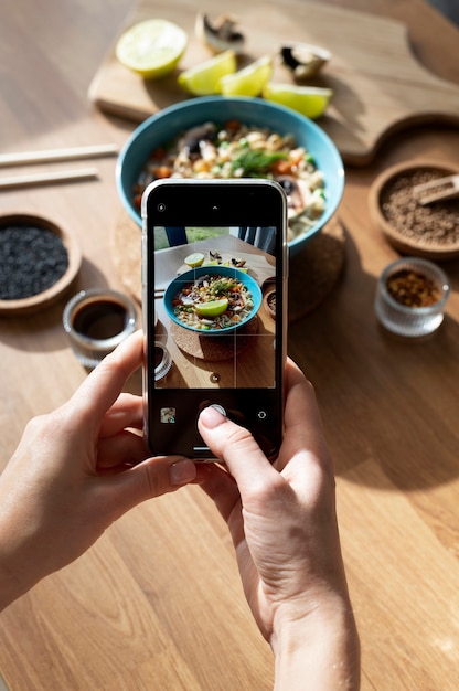 Free photo woman taking photo of bowl of ramen and sliced lemon