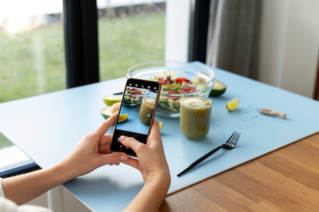 Free photo woman taking photo of a bowl with salad and a smoothie