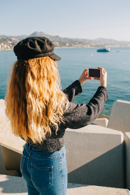 Free Photo woman taking photo of the sea