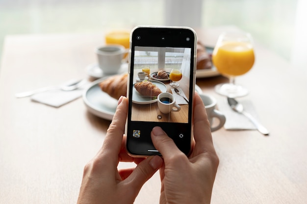 Free Photo woman taking photo of two croissants and two glasses of orange juice