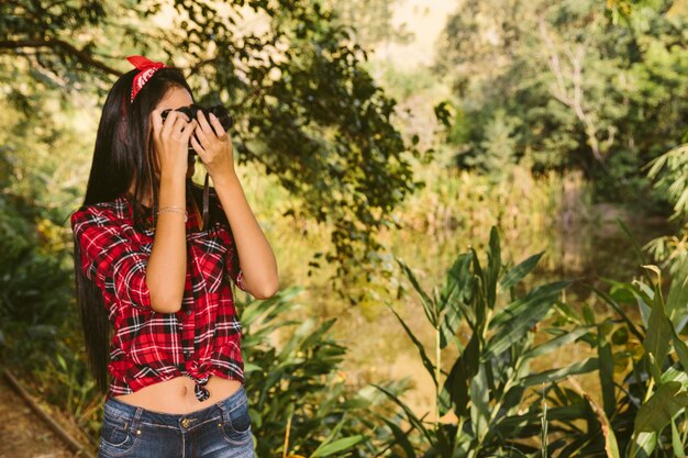 Woman taking photograph with camera in forest