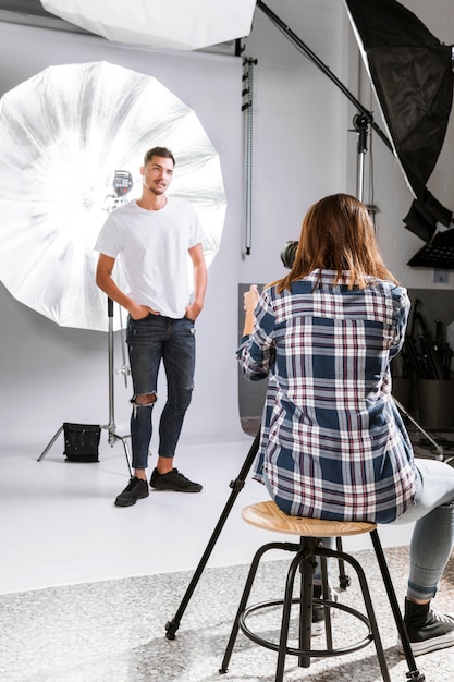 Free photo woman taking photos of handsome man in studio