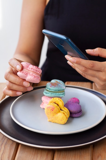 Free photo woman taking photos of heart-shaped macarons on planes with smartphone