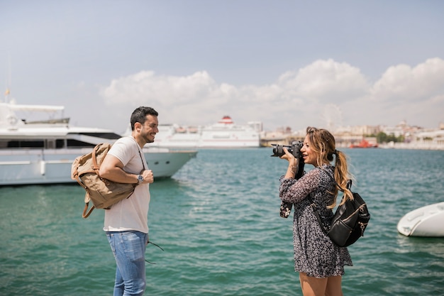 Woman taking pica of her boyfriend on camera near the sea