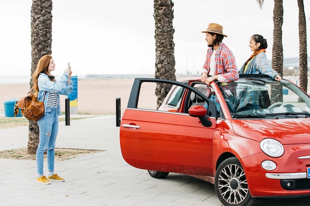 Woman taking picture of couple in car