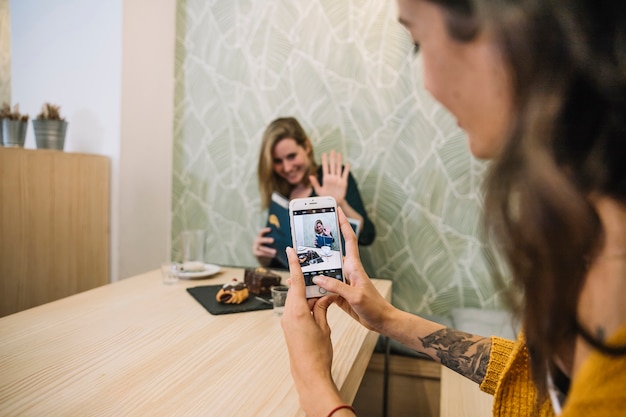 Free photo woman taking picture of friend in cafe