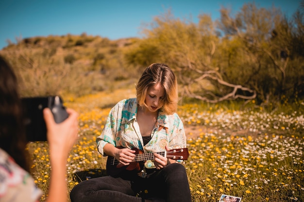 Free photo woman taking picture of friend with ukulele