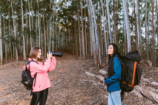 Woman taking picture of her friend in forest