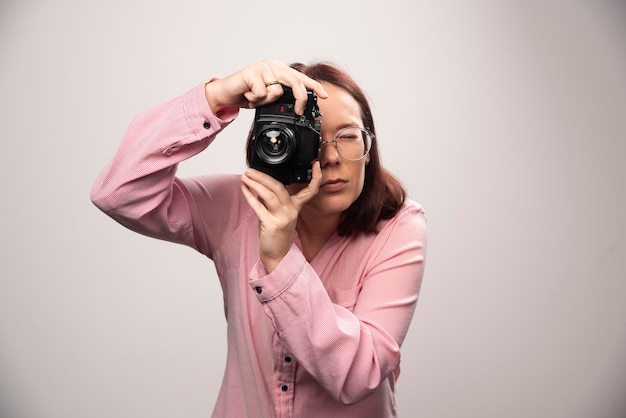 Woman taking a picture with camera on white. High quality photo