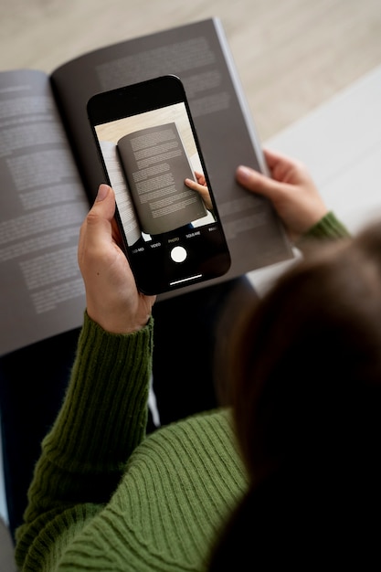 Free photo woman taking pictures of a magazine using her smartphone