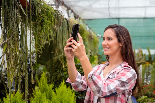 Free photo woman taking pictures of plants in greenhouse