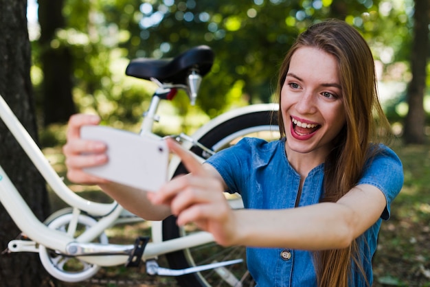 Free photo woman taking selfie next to bicycle