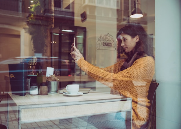 Free photo woman taking selfie in cafe