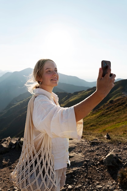 Free Photo woman taking selfie on mountain side view