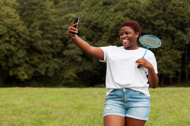 Woman taking selfie outdoors with racket