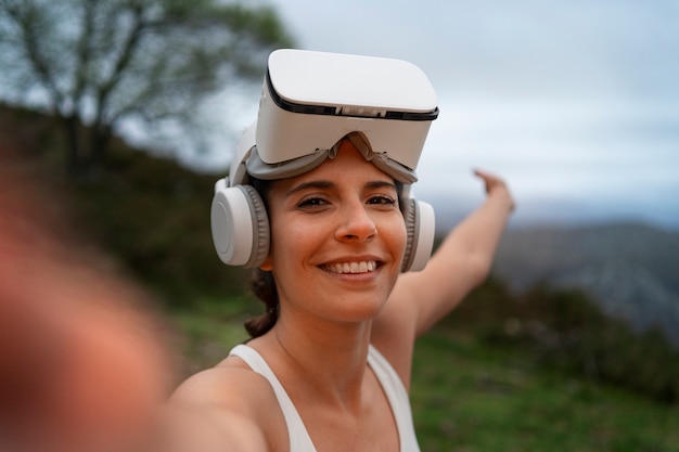 Free photo woman taking selfie while exercising with vr glasses outdoors in nature