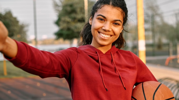 Woman taking a selfie with a basketball