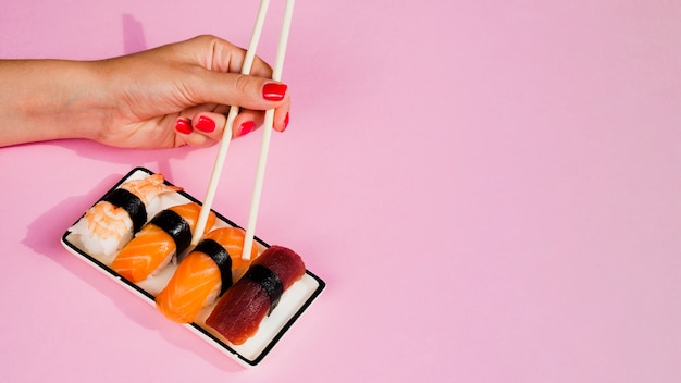 Free Photo woman taking a sushi peace with chopsticks from plate